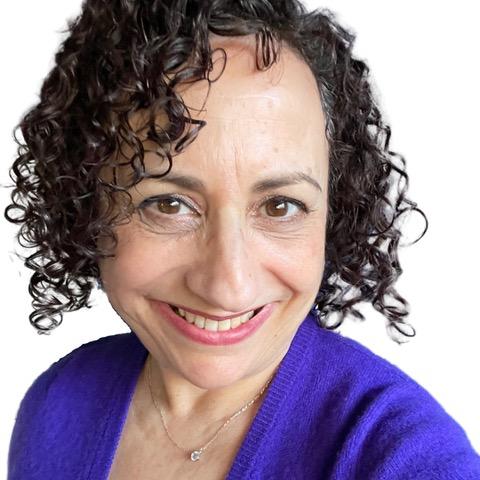 a headshot photo of professional organizer Linda Samuels: a lady with short curly dark hair in a bright purple jumper looking at the camera with a white cut-out background