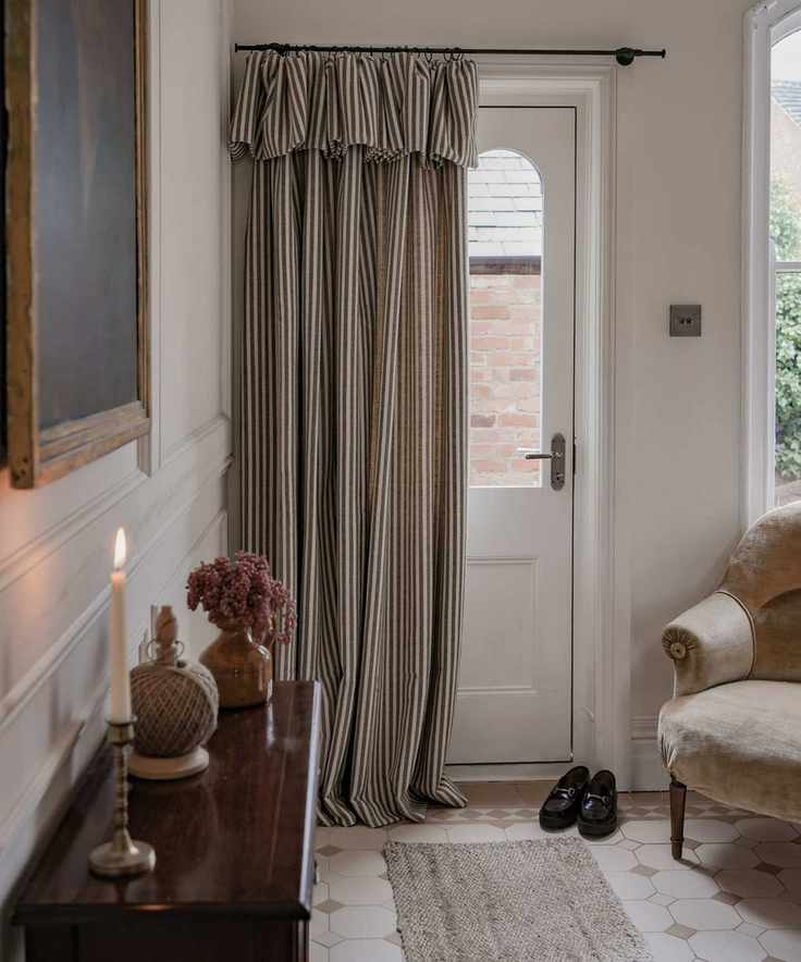 small entryway with a striped front door curtain and cozy chair