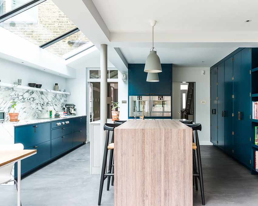 A kitchen with dark blue cabinets and a marble backsplash