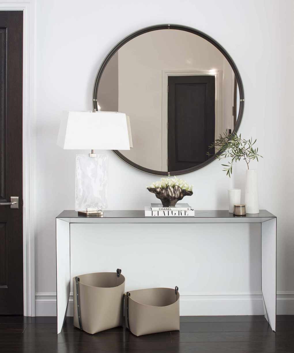A modern hallway with a round mirror and stylish console table