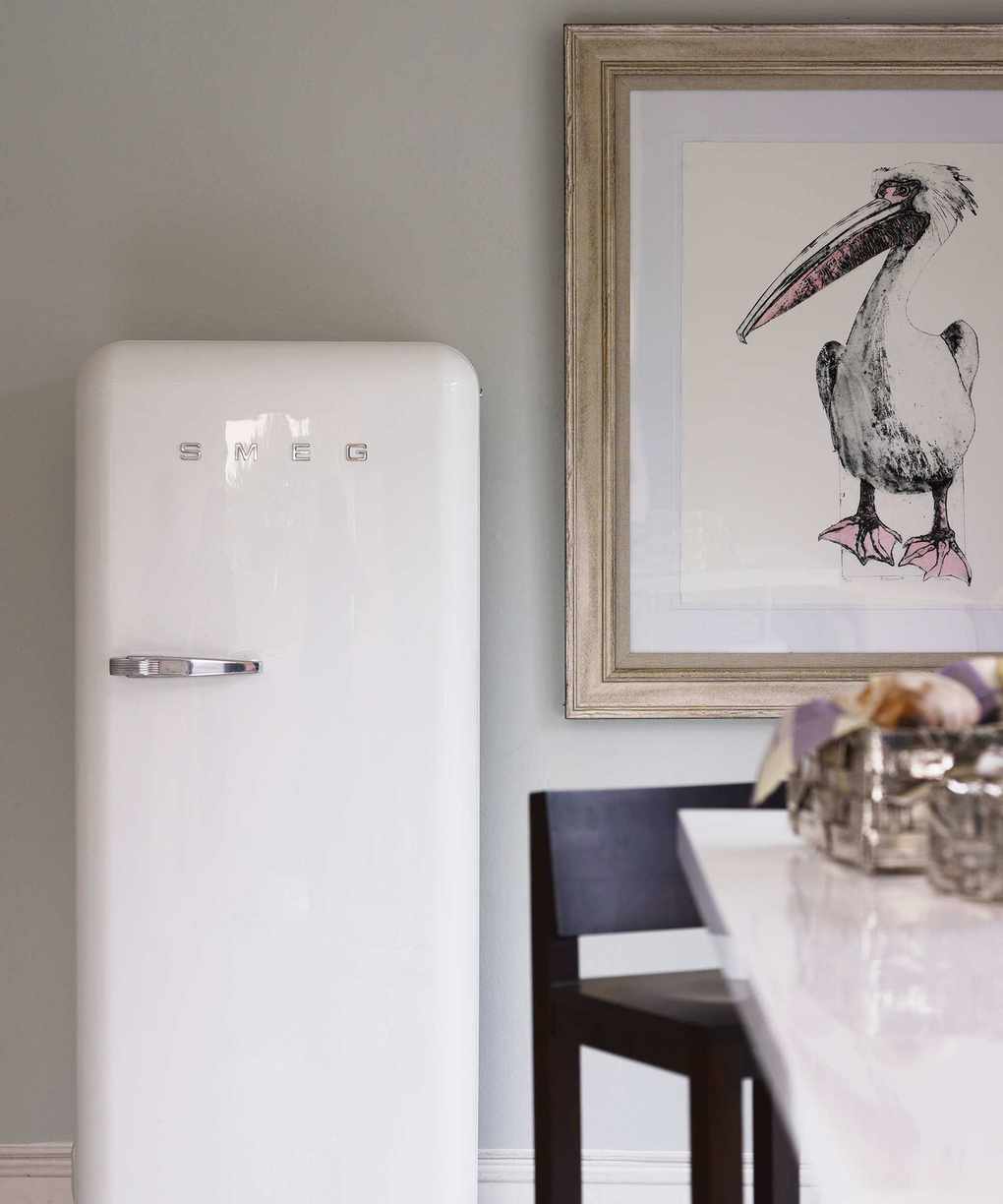 A white, vintage style SMEG fridge against a grey wall