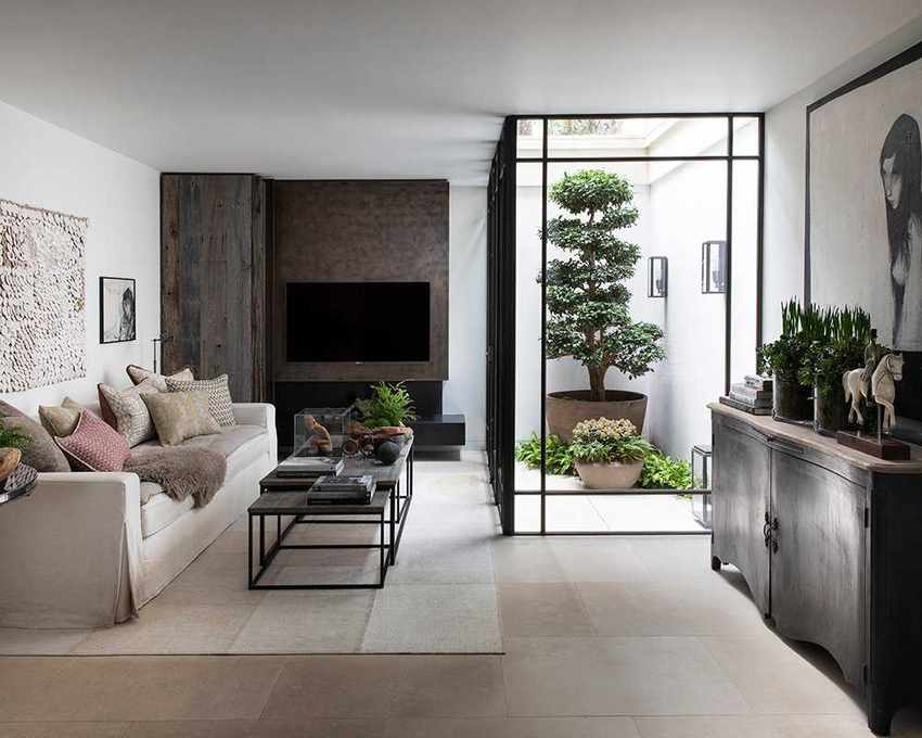 A modern jampandi style basement living room with floor-to-ceiling glass windows looking onto a sunken courtyard willed with zen plants