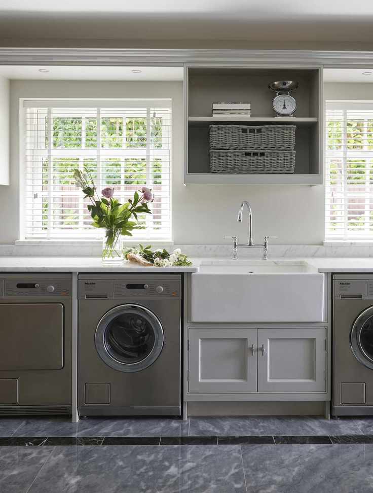 A vase of flowers on a worktop above a washing machine.