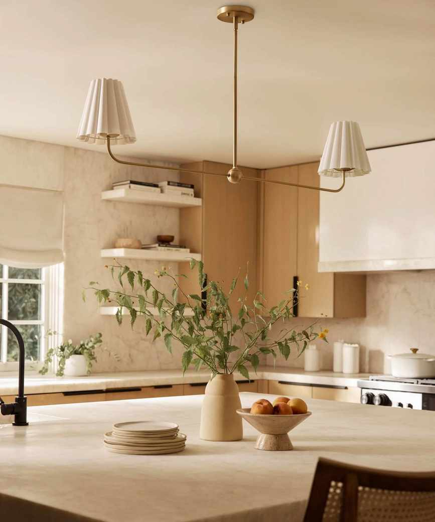 A warm neutral kitchen with a linear chandelier over the island
