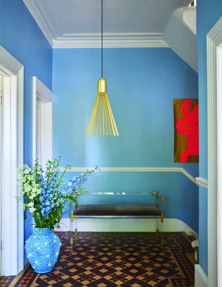 sky blue entryway with artwork, tiled floor, pendant light, bench