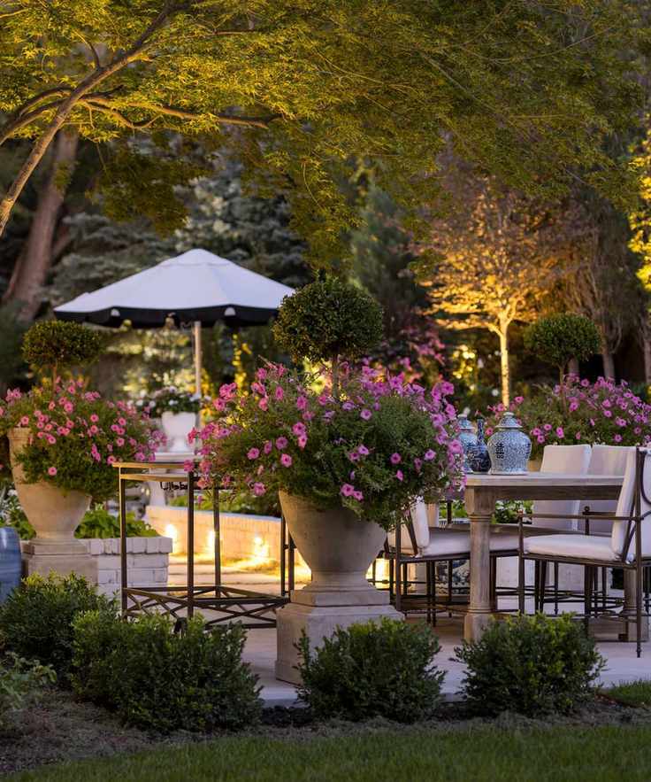 Outdoor seating area with garden uplighters and pots of pink flowers