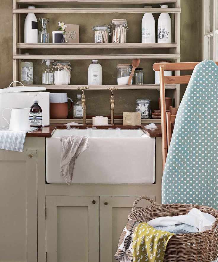 Laundry room with tape cabinets, open shelving with railing to stop bottled or canister products falling off, plus a white under-mounted butler's sink and gold taps