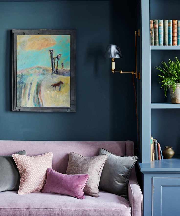 Custom cabinetry in blue beside sofa against blue wall