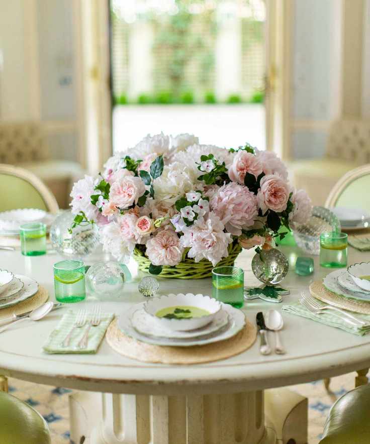 Spring table with peonies bouquet and green glasses and china plates