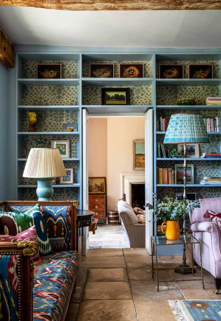 Living room with shelves around door, sofa and armchair and stone floor