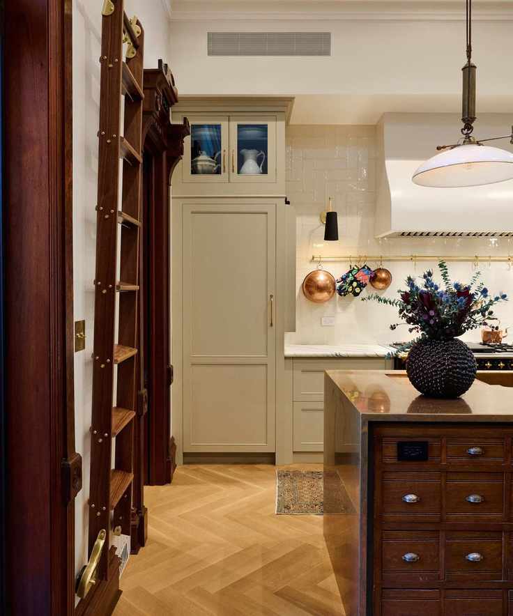 A Brooklyn Brownstone kitchen with beige cabinets, a wooden island, and a brass pot hanger on the wall