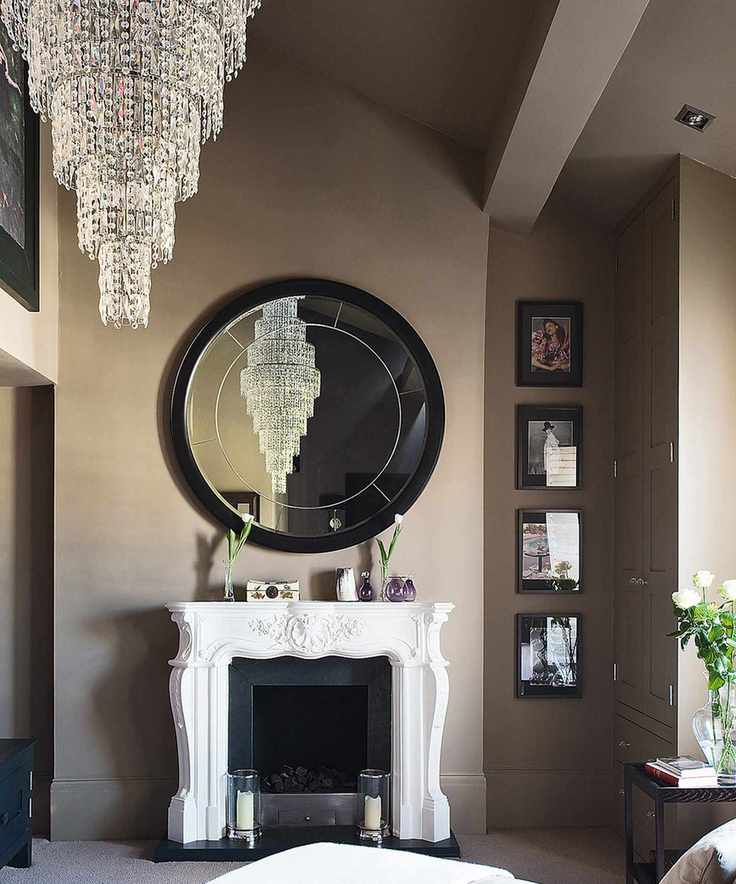A stunning bedroom featuring a large tiered chandelier and a circular mirror