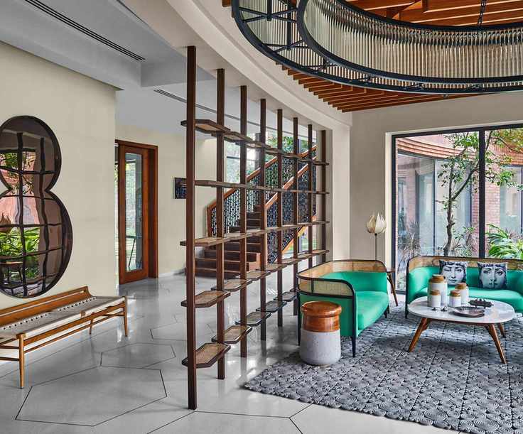 Modern open plan hallway-cum-living room with wooden divide, geometric rug over tile and underneath angular coffee table