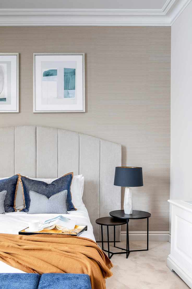 neutral bedroom with pops of orange and navy, black bedside table nest