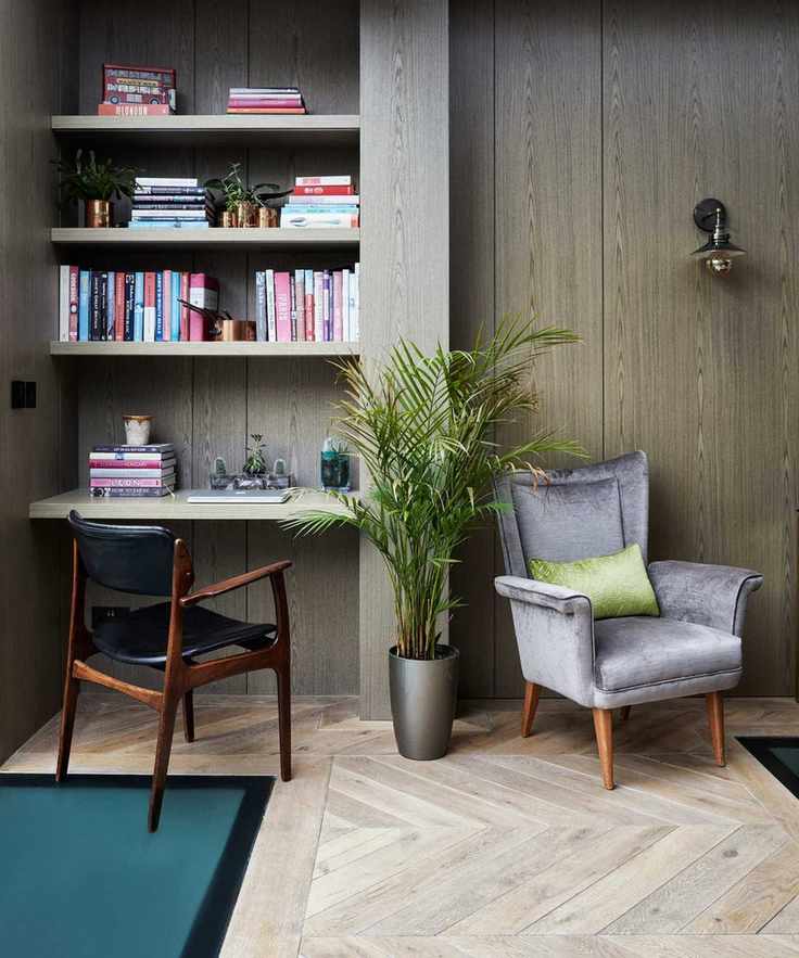 grey armchair in wooden floored room with shelving and desk