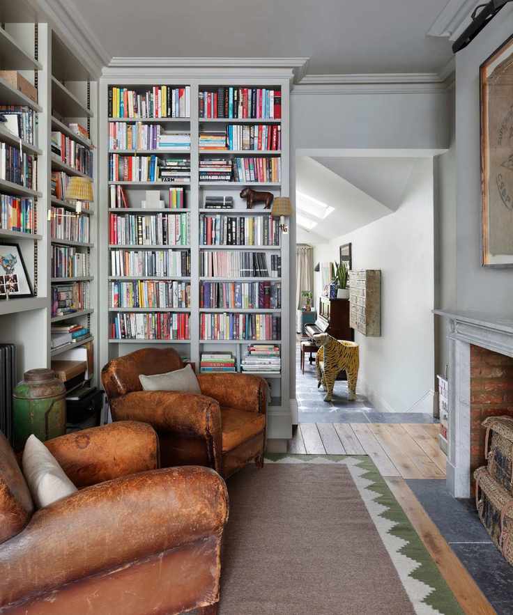 Inviting reading room with floor-to-ceiling bookshelves and brown leather chairs.
