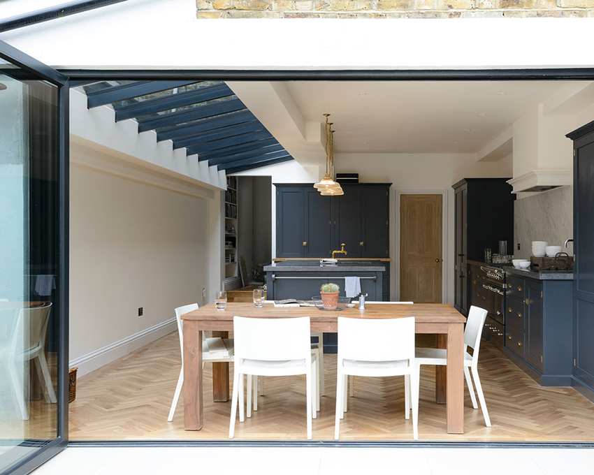 A kitchen extension featuring a wooden dining table and bifold doors