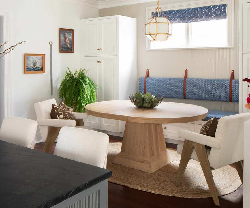 Breakfast nook featuring a round wooden table, cozy armchairs, and an upholstered bench