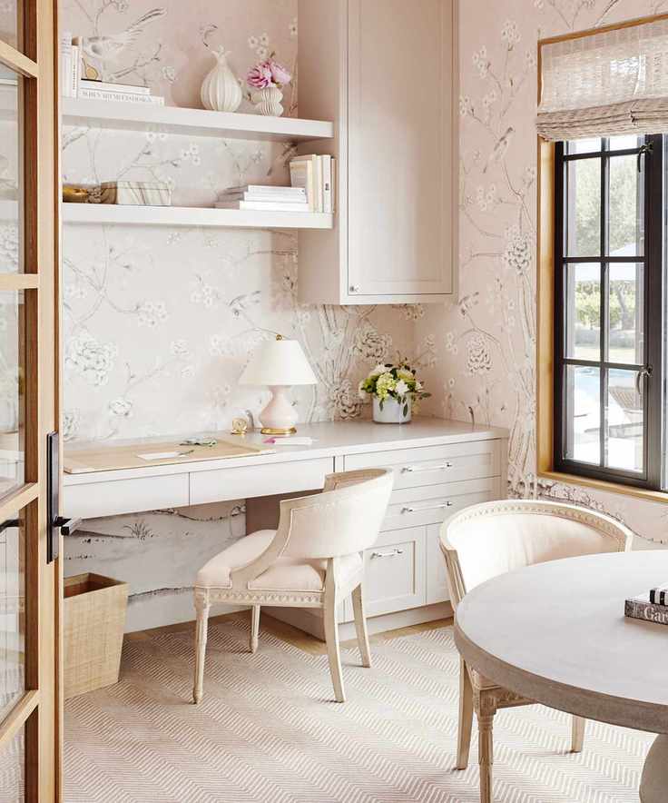 colors that go with light pink, home office with light pink wallpaper, stone cabinetry and chairs, black crittall style window, blind, open shelving, herringbone cream carpet