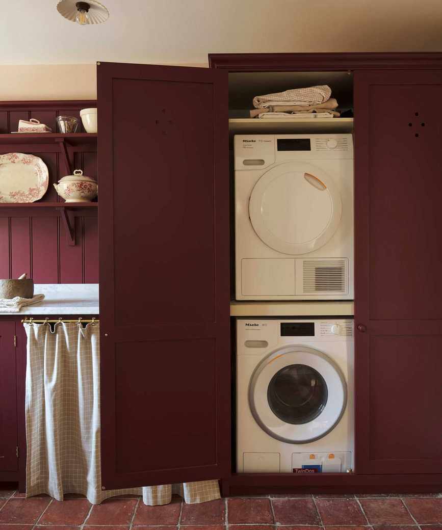 A burgundy laundry room with stacked appliances
