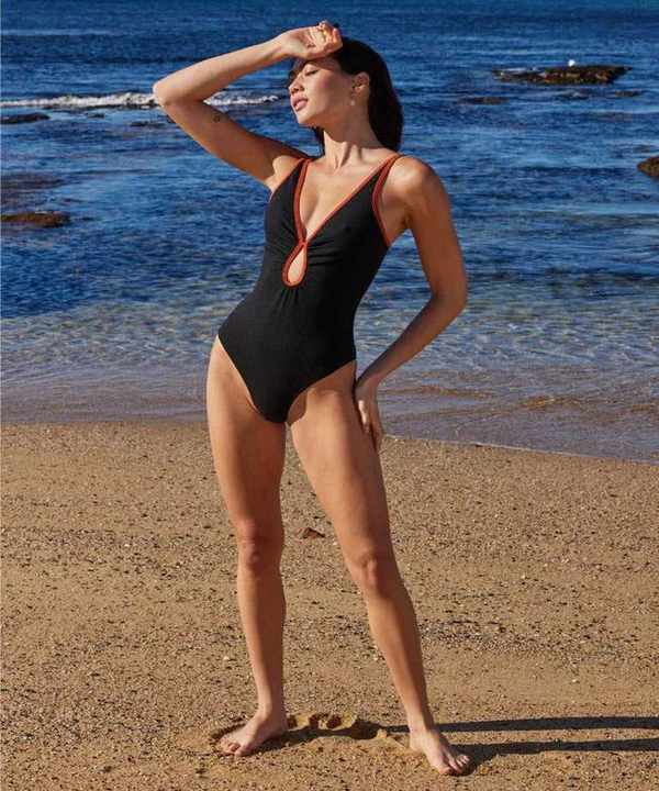Model at the beach in women's black swimwear