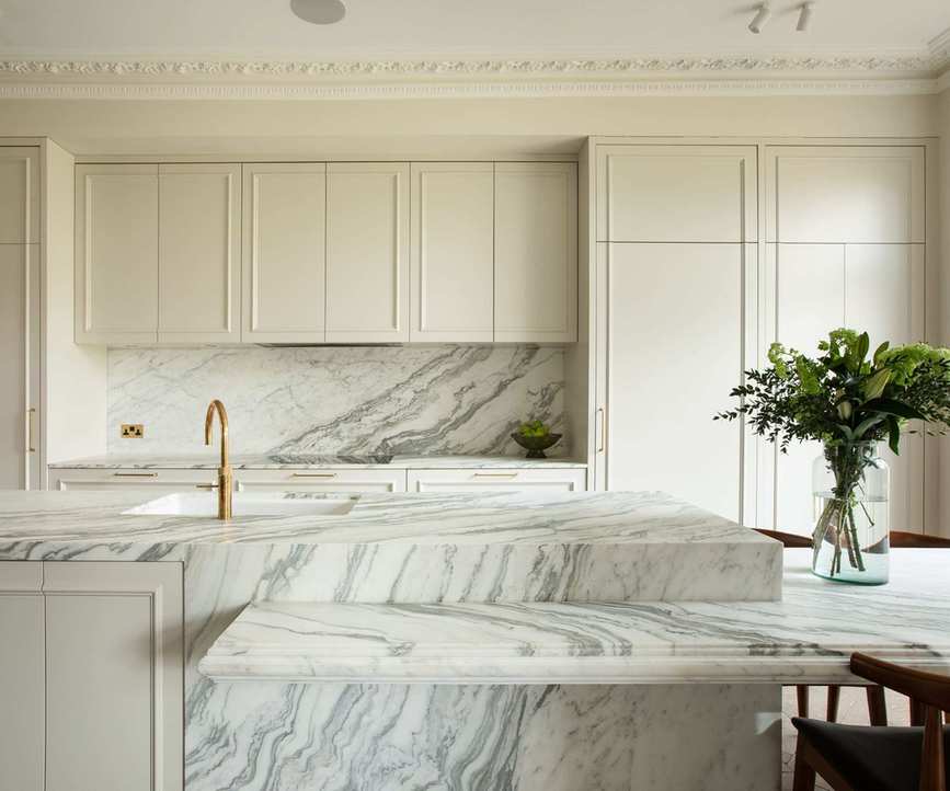 A neutral kitchen with cream cabinets and marble countertops