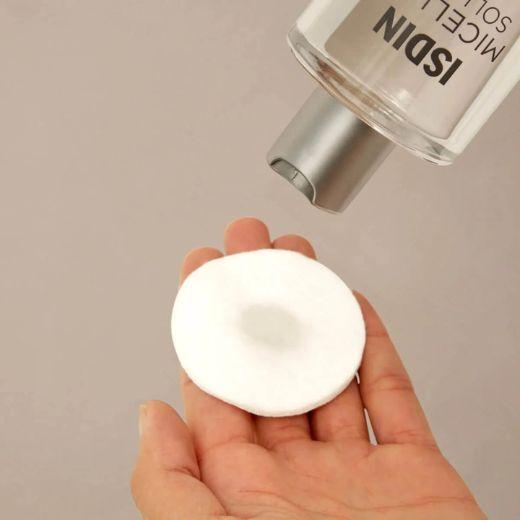 Micellar Solution being applied to cotton round for makeup removal on the eyebrows