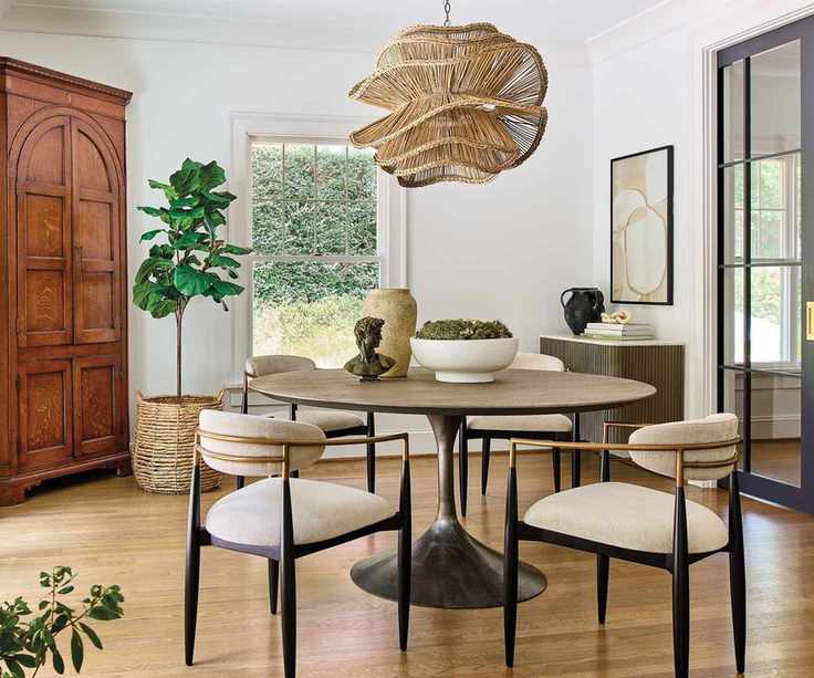 Dining nook with round table and upholstered chairs and rattan lamp shade with white walls