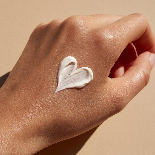 Hand with skincare product in the shape of a heart
