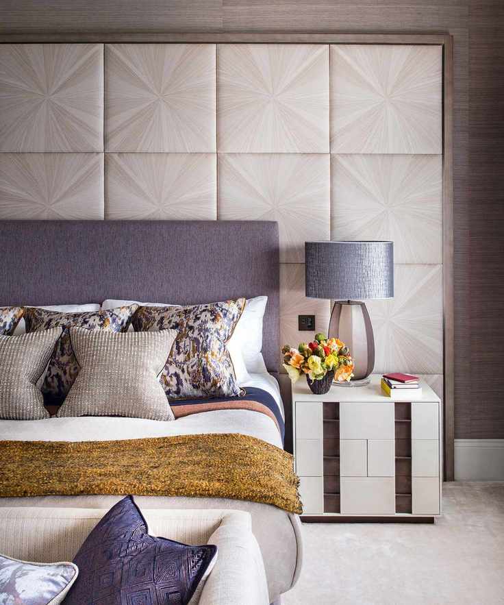Stylish bedroom accent wall featuring modern square wall paneling behind a bed with a large blue headboard and mustard yellow throw.
