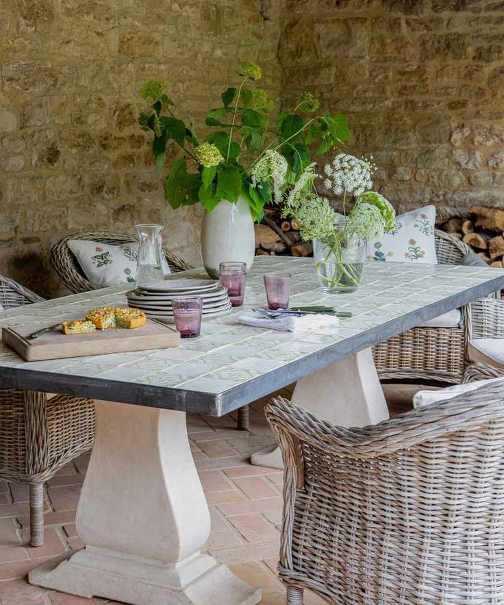 Tiled dining table with rattan chairs in a stone outdoor building