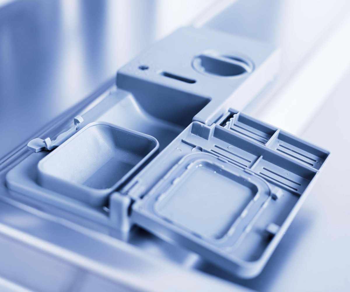 Up close of a clean, empty dishwasher detergent dispenser