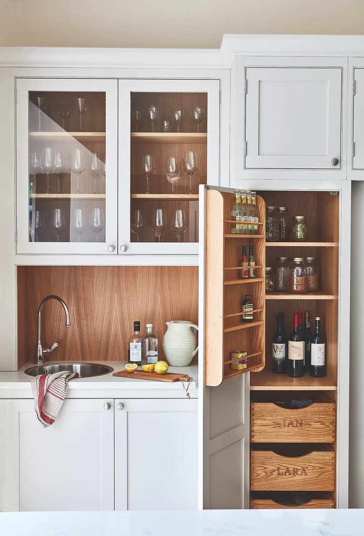 Kitchen sink and counter with cabinets above and below and to one side in neutral painted finish