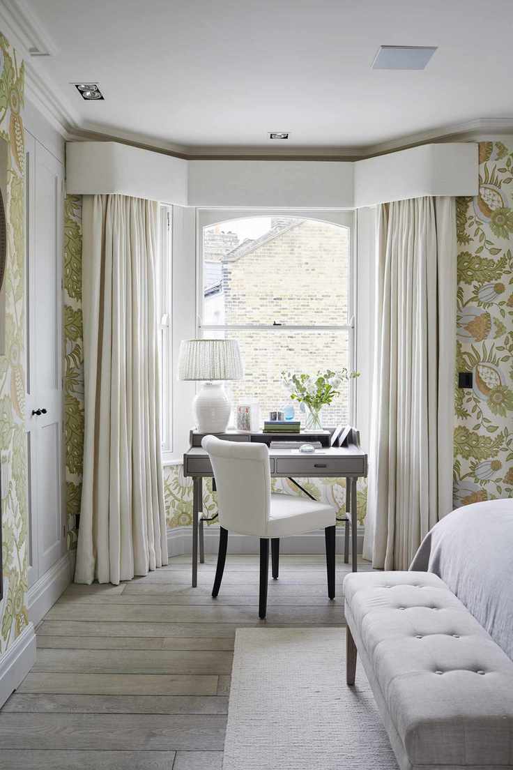 Cream curtains, grey office table, white chair with black legs