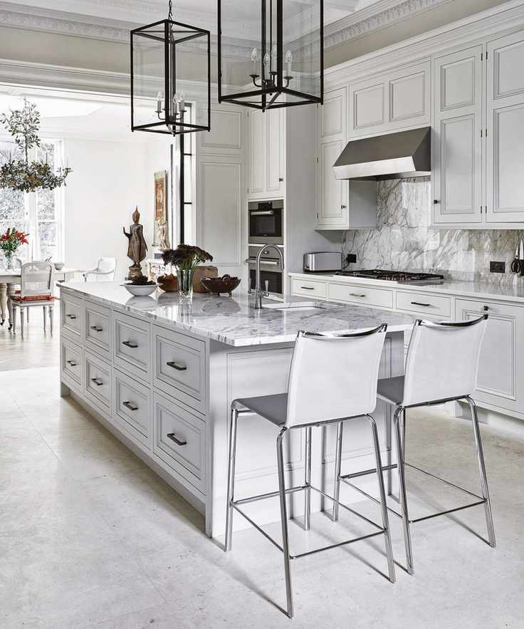 A white kitchen where marble backsplash ideas seamlessly flow into the countertops and island.
