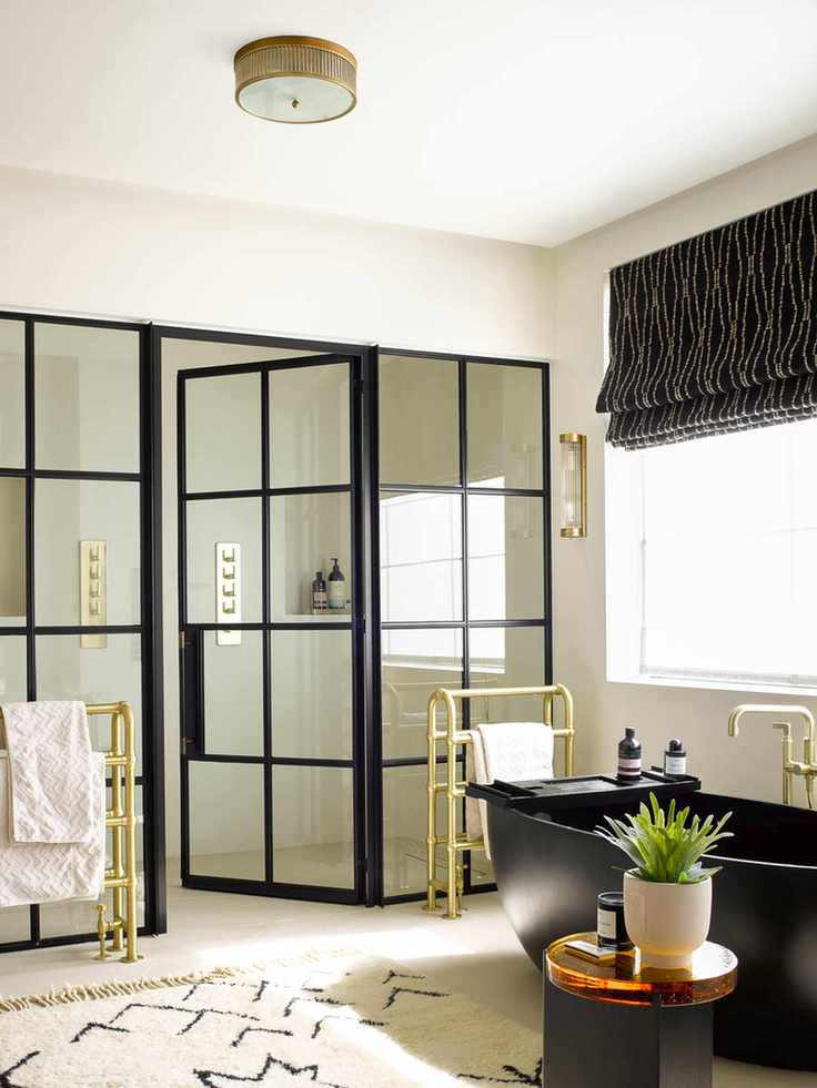 bathroom with walk in shower, black tub, window blind, rug, radiators, side table, crittal doors