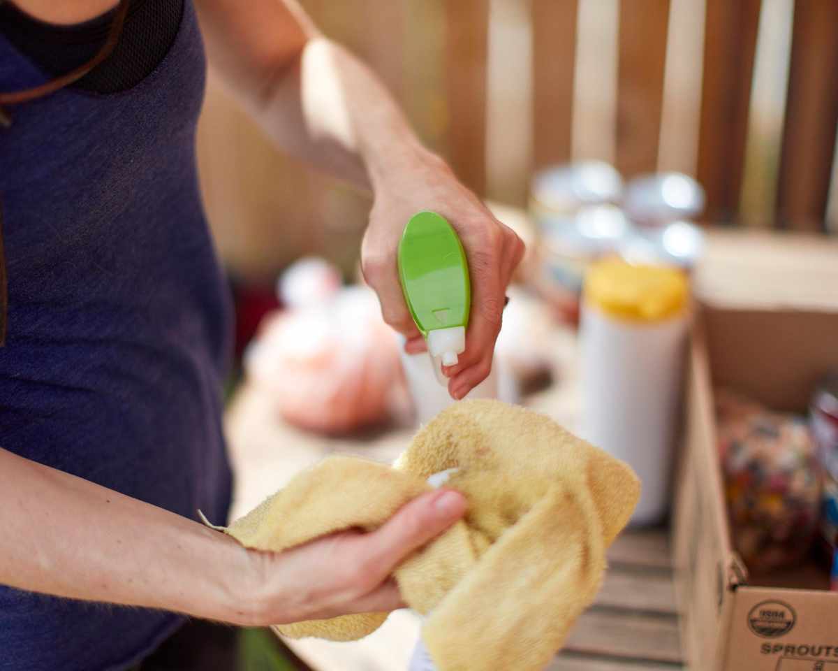 Woman spraying cleaning spray on cloth
