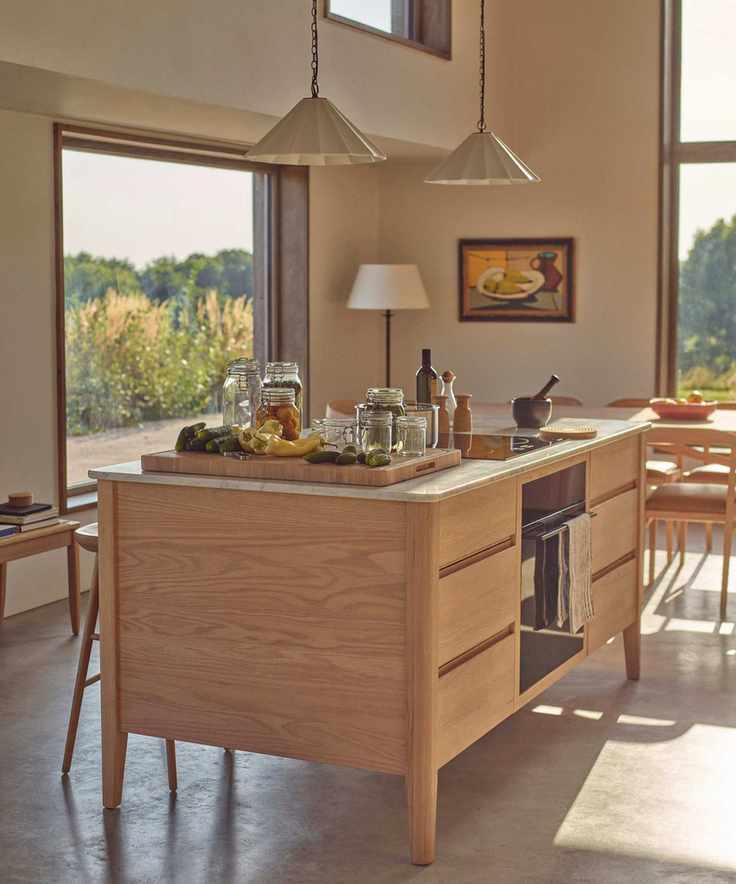 A neutral kitchen with a wooden island housing an oven and lots of drawer storage