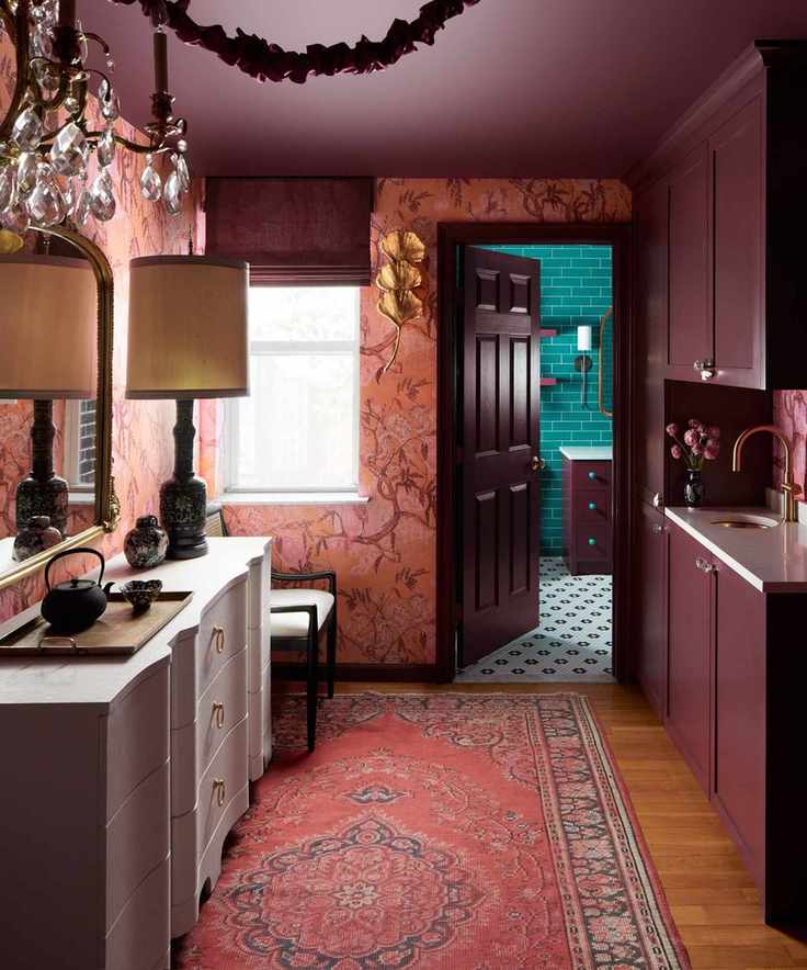 A small kitchen with plum cabinets and playful wallpaper.