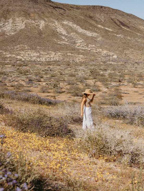 Woman standing in field with butter yellow flowers.