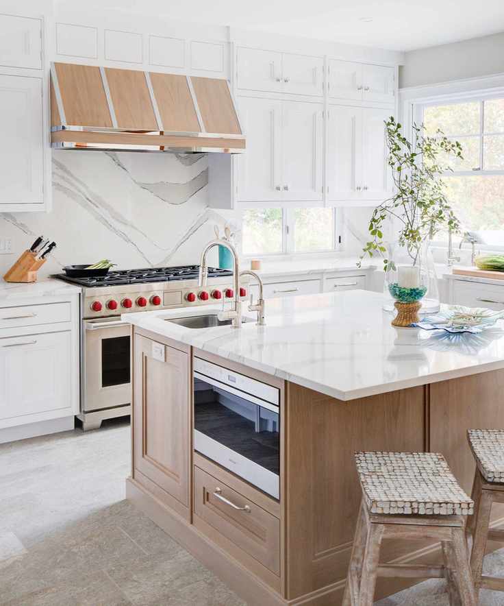 Kitchen with white cabinets and wood island, range, marble backsplash and neutral tile floor