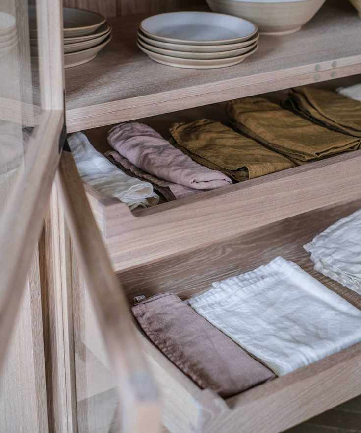 Cabinet with pullout drawers holding different colored napkins and plates