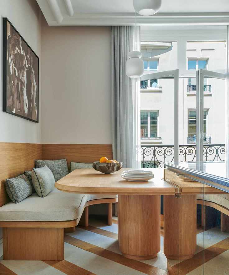 art deco inspired kitchen dining area with blue and wood striped floor and curved furniture, the ceiling has bold molding for an art deco feel