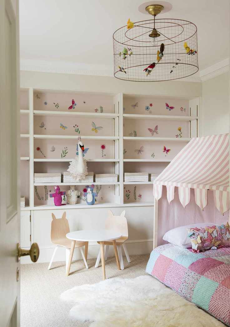 Pastel pink girl's bedroom with butterfly wallpaper behind shelves