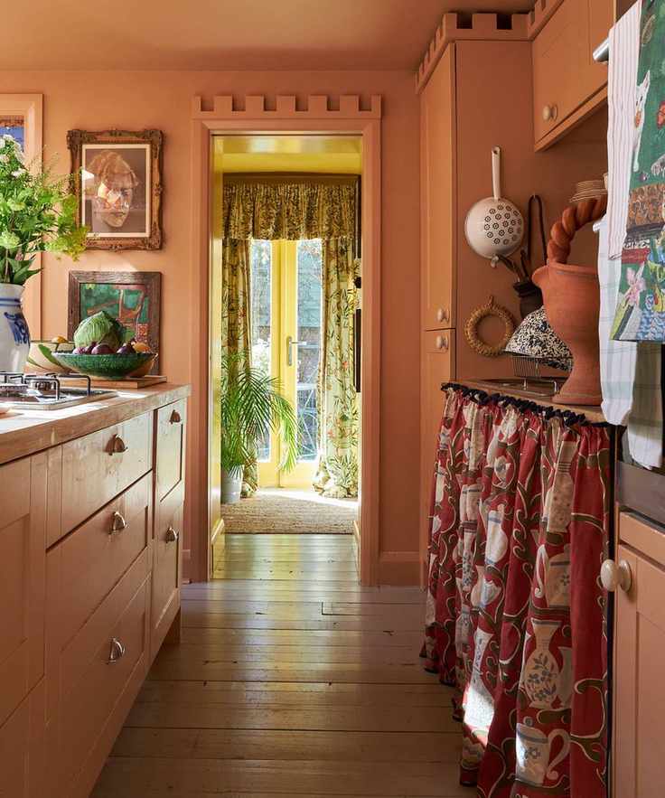 warm orange kitchen color drenched to match the cabinets with a rust red cabinet skirt and terracotta kitchen counter decor