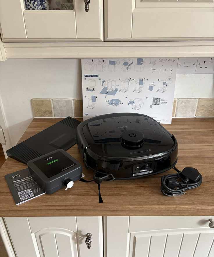 Contents of the eufy Omni E25 box on a wooden kitchen counter