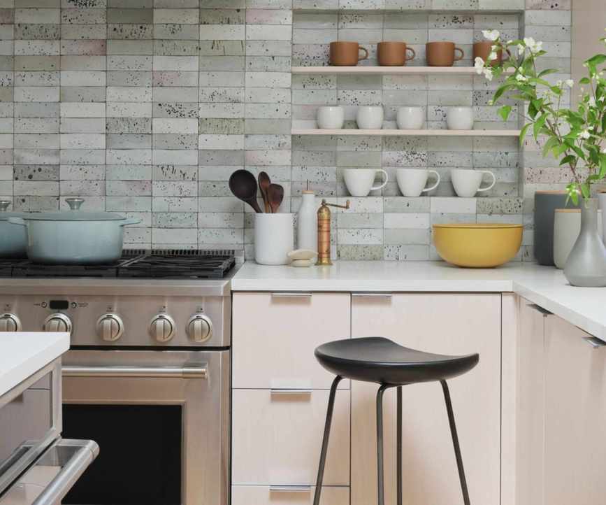 A coastal West Elm kitchen with pink cabinets, chrome hardware, and gray wall tiles