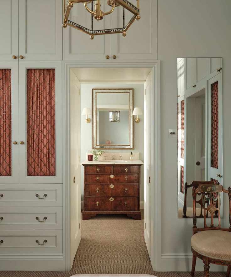 Pale blue bedroom with built-in drawers and cupboards with a hallway looking the bathroom with a vintage sink and mirror
