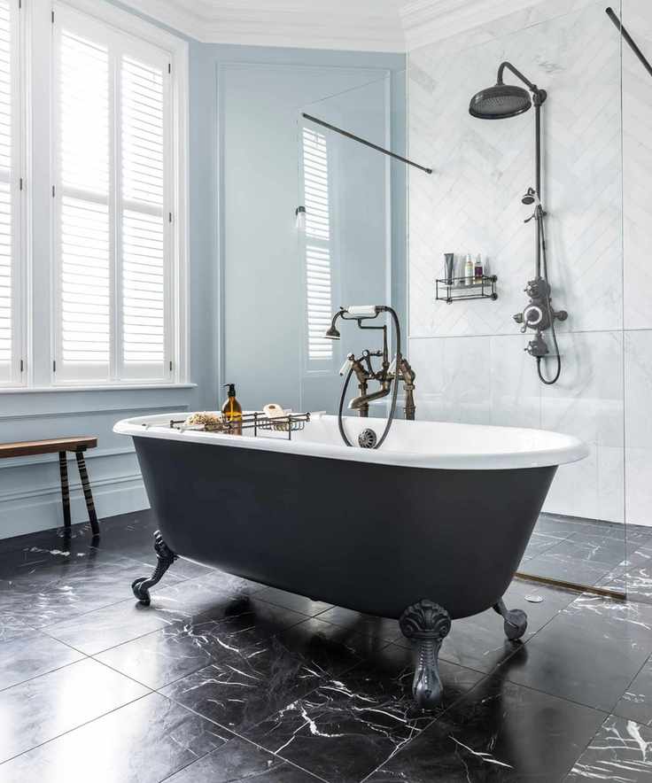 White tiled bathroom with freestanding matte graphite gray bathtub and walk in shower with chevron tiling