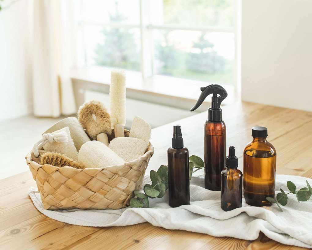 amber spray bottles with cleaning sponges and brush in basket